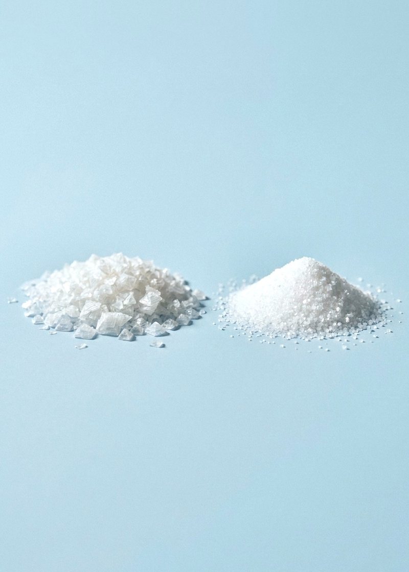 Flaky sea salt beside fine potassium chloride crystals