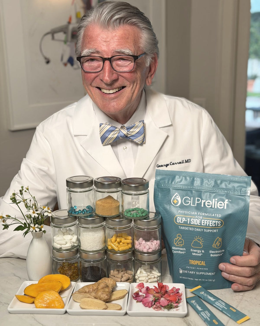 Dr. George Carroll in his white coat and bow tie, smiling at a kitchen counter with a bag of GLPrelief and jars of its ingredients