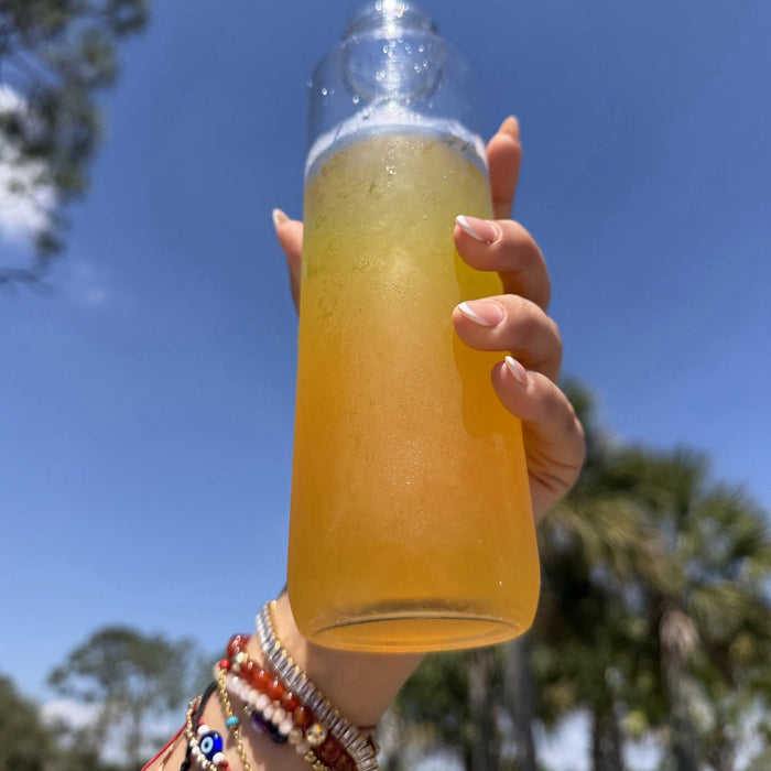 A bottle of the mixed golden GLPrelief drink held up against a blue Florida sky.