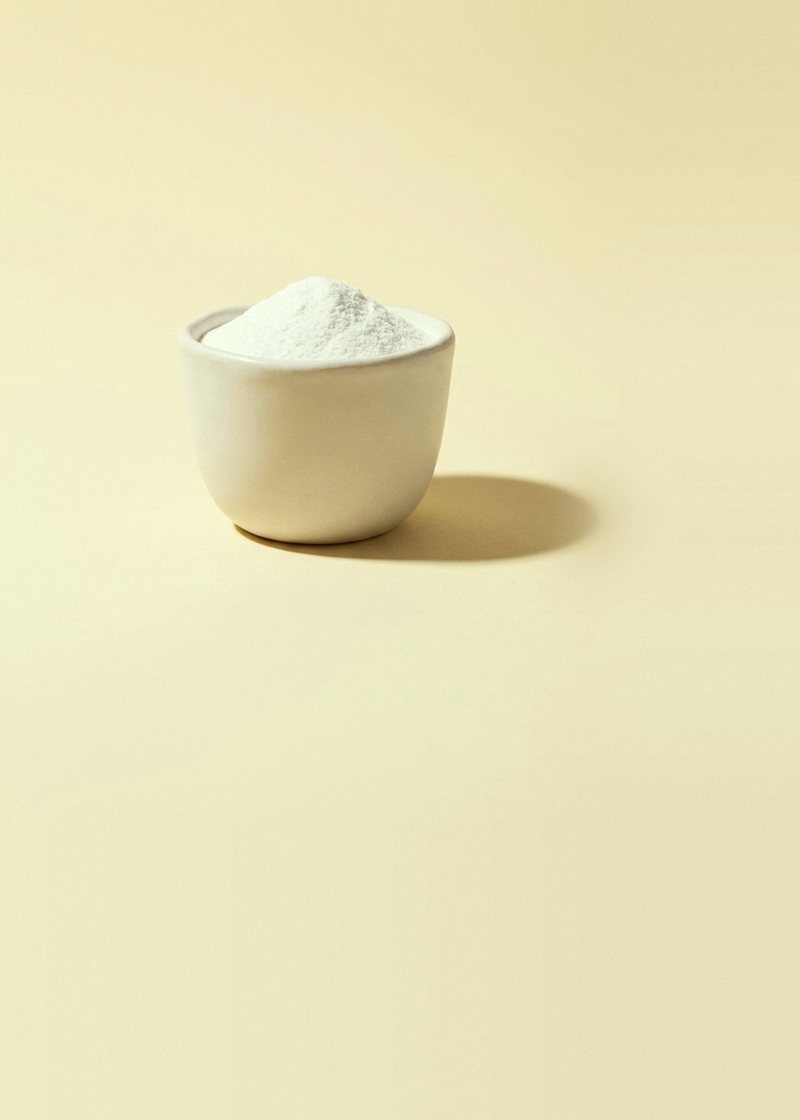 White vitamin B5 (calcium pantothenate) powder in a small stoneware cup