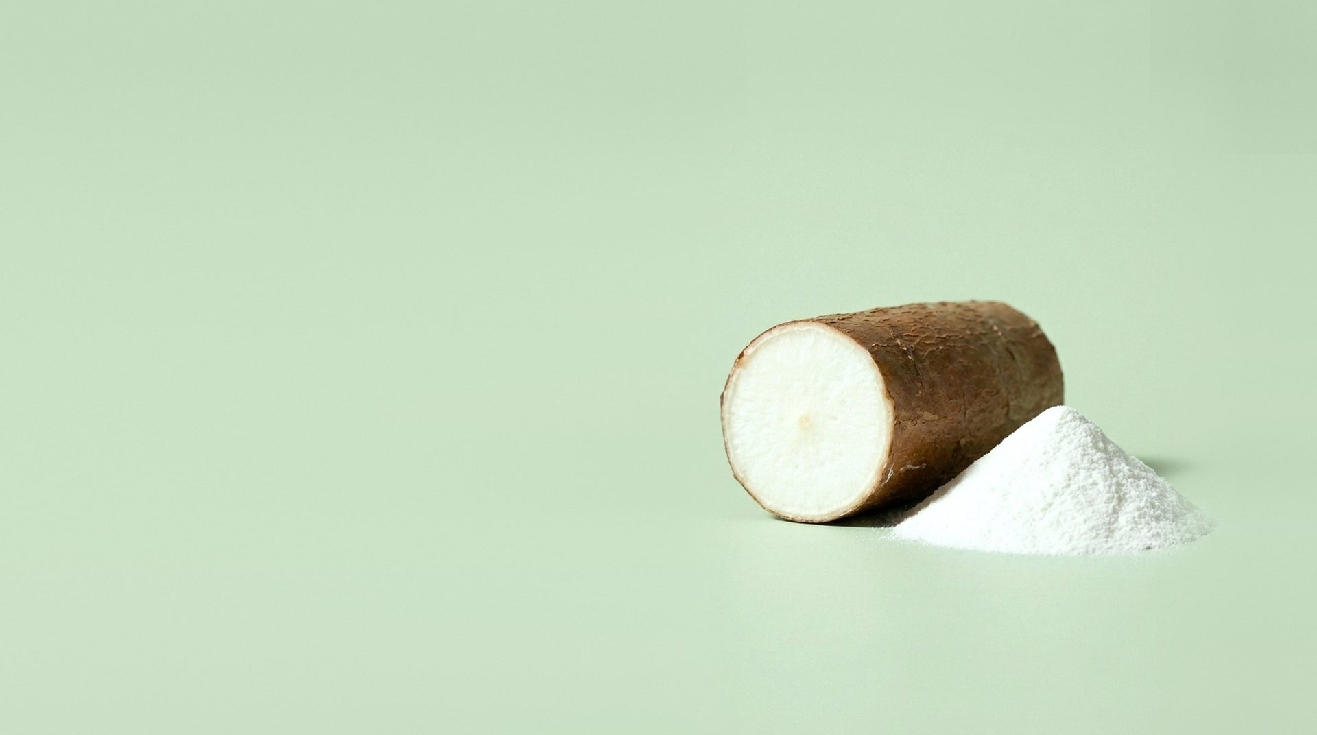 A cut cassava root beside a mound of white resistant dextrin powder