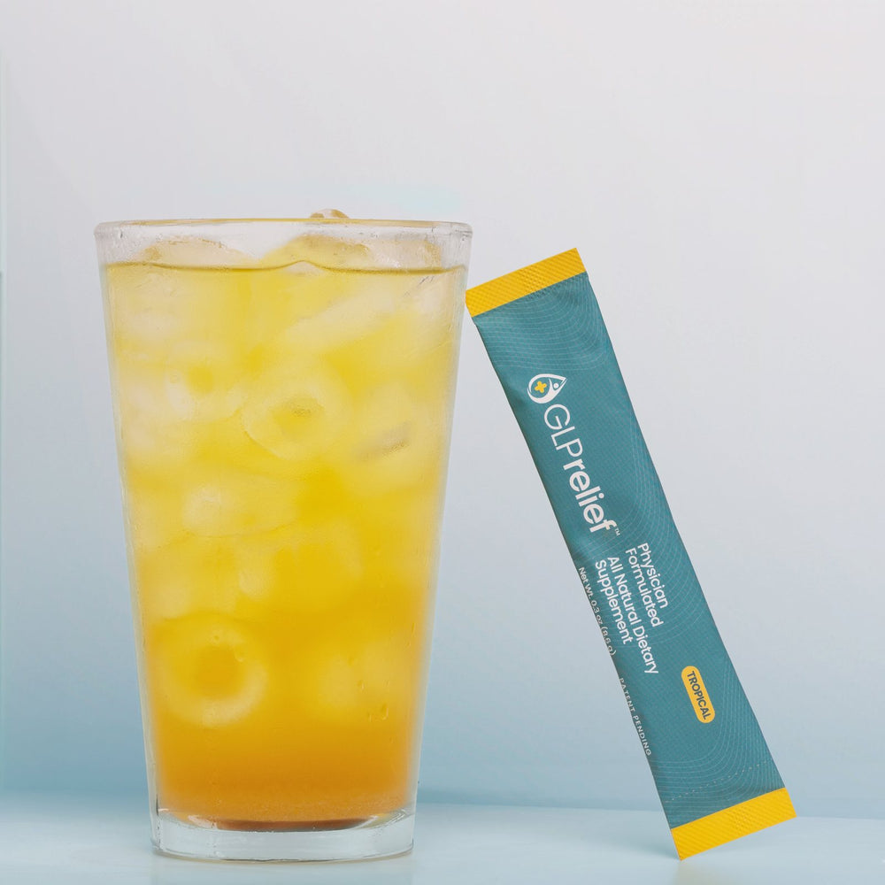 A glass of the golden GLPrelief drink over ice with a GLPrelief stick pack leaning against it