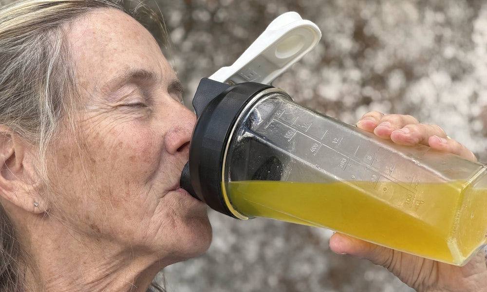Barbara Carroll taking a sip of GLPrelief from a clear shaker bottle