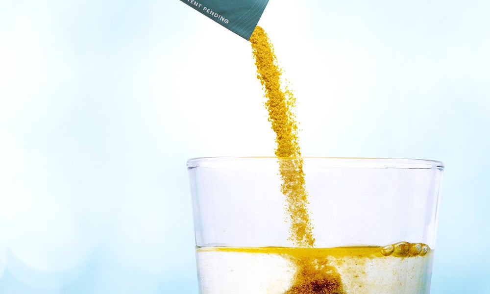 Powder pouring from a GLPrelief stick pack into a glass of water